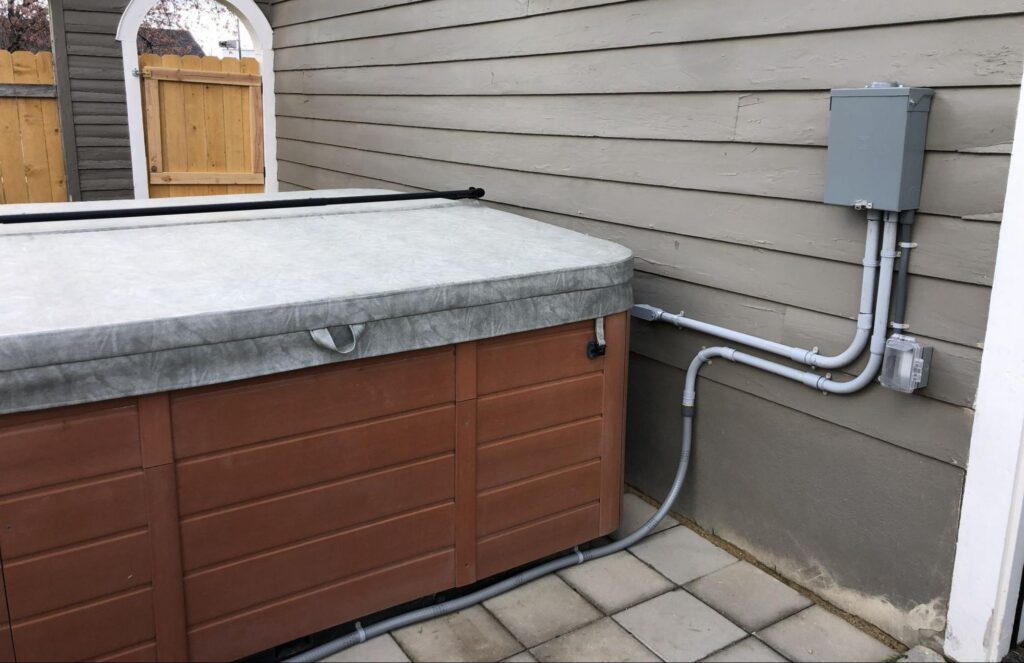 Finished hot tub wiring installation in Boise showing conduit and a GFCI disconnect box.