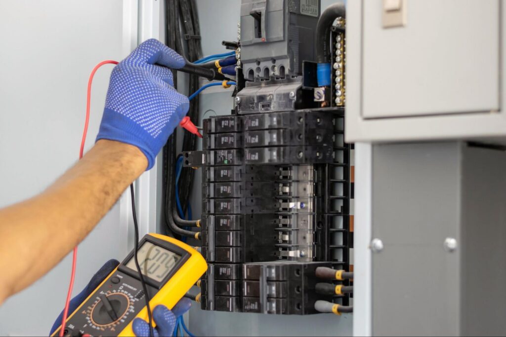 Electrician testing breakers in an open panel during dedicated circuit installation in Boise, ID