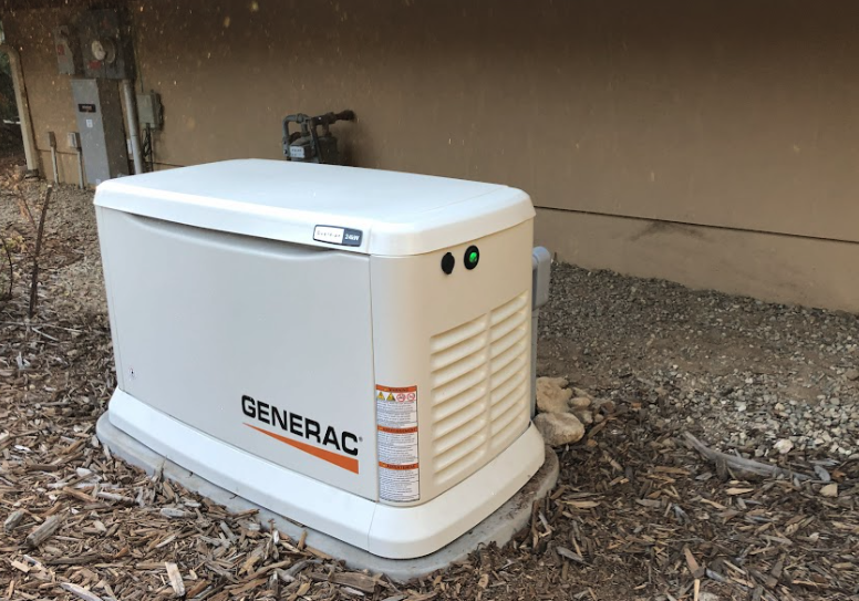 Standby generator installation at a Caldwell, ID home, mounted on a concrete pad beside the panel.