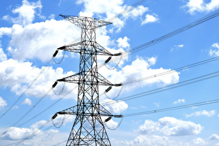 High-voltage power lines and a transmission tower against a blue sky over Boise, Idaho.